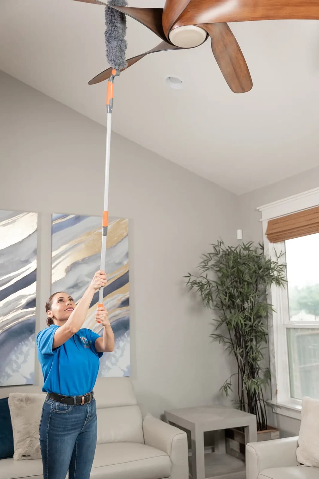 A Trustworthy cleaner dusting ceiling fan blades with an extension duster in Austin, TX